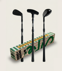 Three black toddler golf clubs (driver, putter and wedge) in front of a cardboard her box with Mini Hoshi branding. A studio shot on an off-white background. 